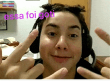 a man wearing headphones making a middle finger sign with the words essa foi goti in the background