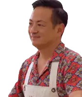 a man wearing an apron and a red and blue shirt smiles