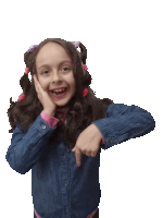 a little girl with pigtails and a denim jacket is pointing at something