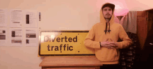 a man wearing a yellow hoodie stands in front of a sign that says diverted traffic