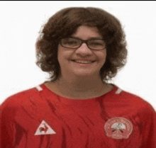 a woman wearing glasses and a red shirt is smiling for the camera