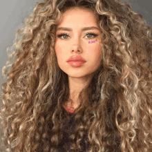 a woman with long curly hair has the word baby written on her face