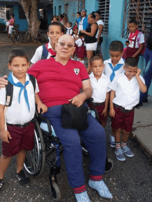 a man in a wheelchair is posing for a picture with a group of children