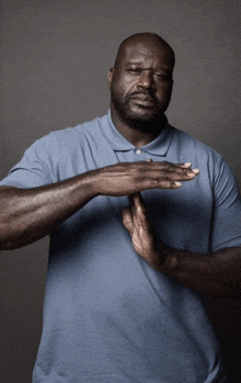 a man wearing a blue shirt is making a stop sign with his hands