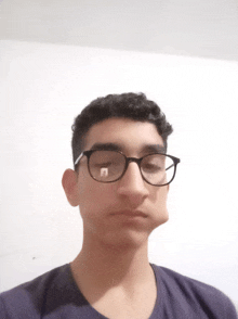 a young man wearing glasses and a purple shirt is making a funny face