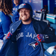 a man wearing a blue jays jersey is smiling in the dugout