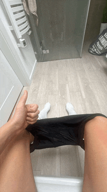 a person giving a thumbs up while sitting on a toilet in a bathroom