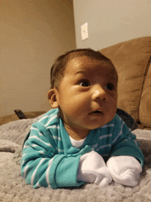 a baby wearing a blue and white striped shirt is laying on his stomach