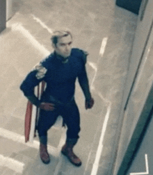 a man in a superhero costume is standing in a hallway holding a shield .