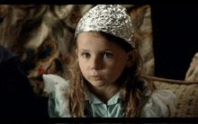 a little girl wearing a tin foil hat is looking at the camera