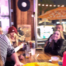 a group of people sit at a table in front of a sign that says ' coca cola ' on it