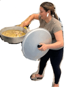 a woman is holding a pot full of food