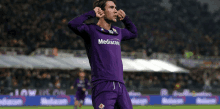 a soccer player wearing a purple jersey with mediacom on it