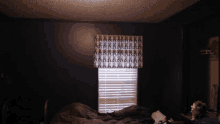 a dark bedroom with a bed and a window