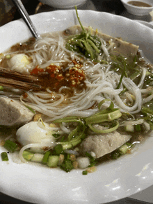 a white bowl filled with noodles meatballs and vegetables