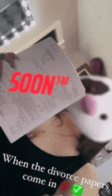 a woman is holding a piece of paper over her head with the words `` soon '' written on it .