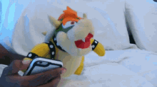 a person is holding a bowser stuffed animal in their hands