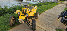 a yellow atv is parked on a sidewalk near a body of water