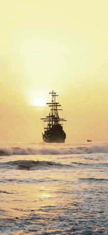 a sailboat in the ocean at sunset with a boat in the distance