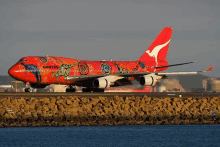 a red qantas plane is sitting on the runway