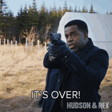 a man holding a gun with the words it 's over hudson & rex