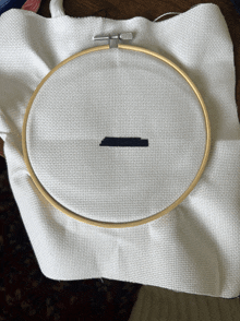 a cross stitch hoop is sitting on a piece of white cloth