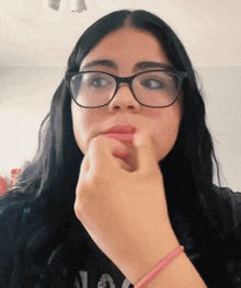 a woman wearing glasses and a pink bracelet holds her mouth open