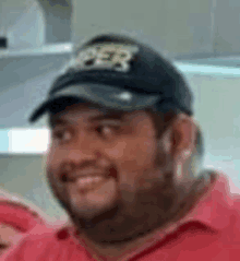 a close up of a man wearing a baseball cap and a red shirt .