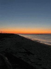 a sunset over a body of water with a silhouette of a person on the shore