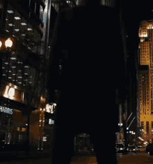 a person is walking down a city street at night in front of a harris store