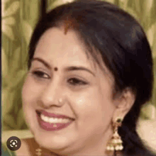 a close up of a woman 's face with a bindi on her forehead smiling .