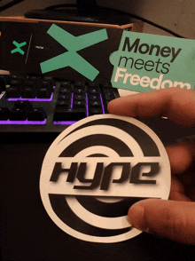 a person holds a sticker that says hype in front of a keyboard