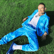 a man in a blue suit is laying in the grass with a tattoo on his face that says 666