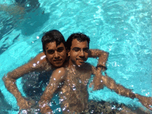 two boys are swimming in a pool and one has glasses on