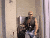 a shirtless man in a leather vest is walking in a room