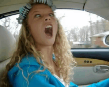 a woman with curlers in her hair is driving a car