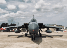 a fighter jet is parked on a runway with smoke coming out of the tail