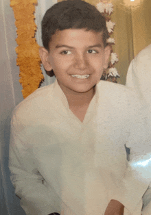 a young boy wearing a white shirt is smiling