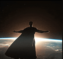 a silhouette of a man in a cape with his arms outstretched