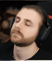 a man with a beard is wearing headphones with his eyes closed