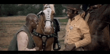 a man in a sheriff 's uniform talks to another man standing next to a brown horse