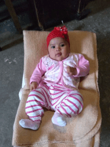 a baby wearing a pink and white outfit with a bear on it is sitting on a blanket