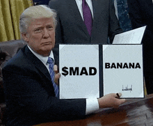 a man in a suit and tie is holding a sign that says $ mad and banana