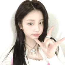 a girl wearing a necklace and a ring is giving the peace sign