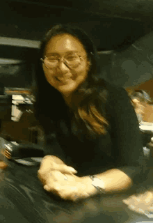 a woman wearing glasses and a watch smiles at the camera