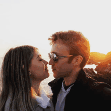 a man and a woman are kissing in front of the ocean