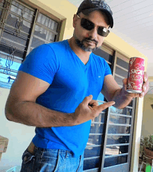 a man in a blue shirt holds up a can of skol beats