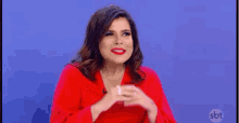 a woman in a red dress is sitting in front of a blue background .