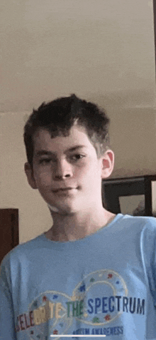 a young boy is wearing a blue t-shirt that says celebrate the spectrum on it .