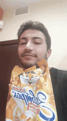 a man is holding a bag of cat food with a cat on it 's face